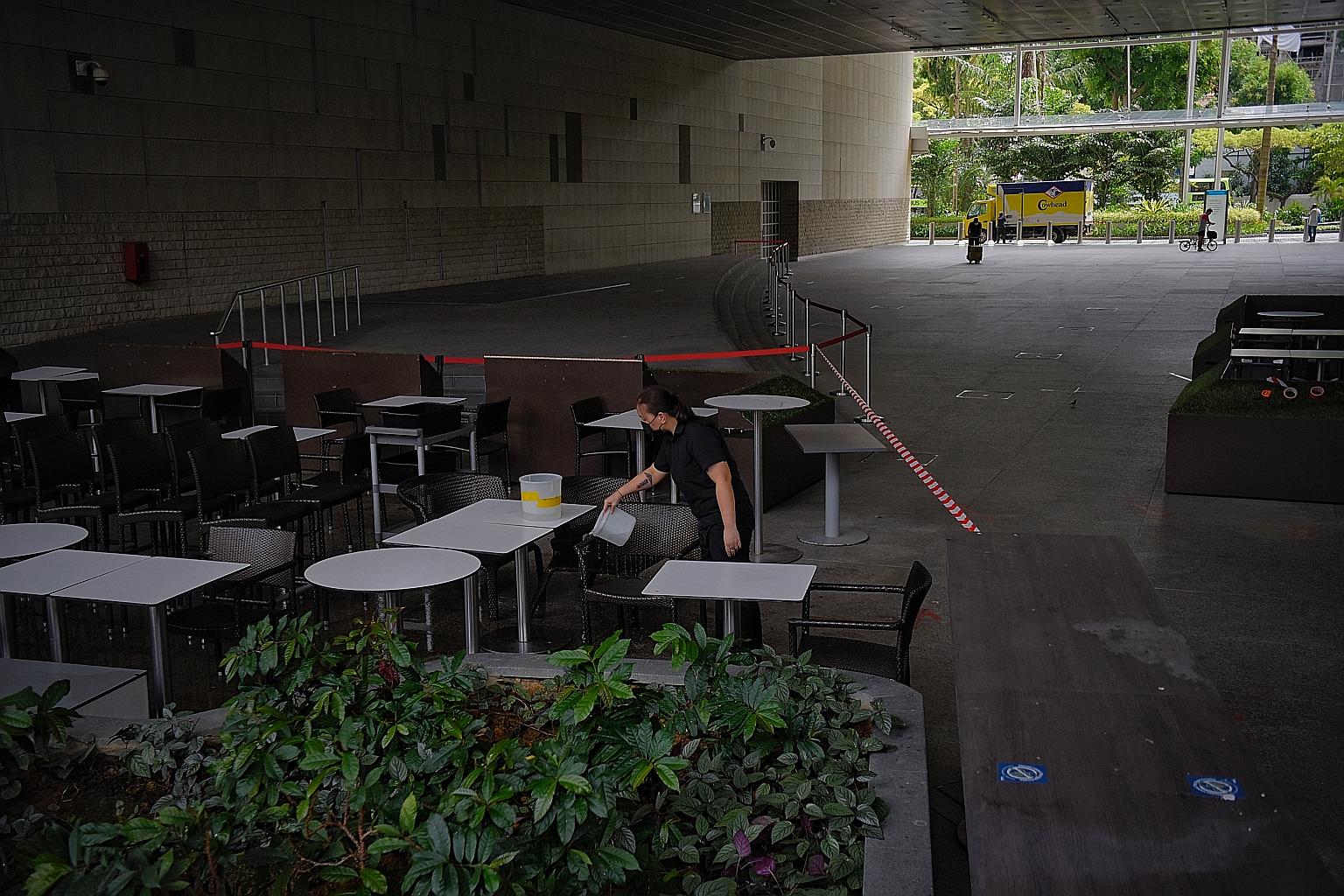 A staff member of a Hanis Cafe and Bakery outlet at the National Library Building cleaning tables and chairs yesterday in preparation for tomorrow, when dining in will be allowed with a cap of two patrons per table. ST PHOTO: MARK CHEONG