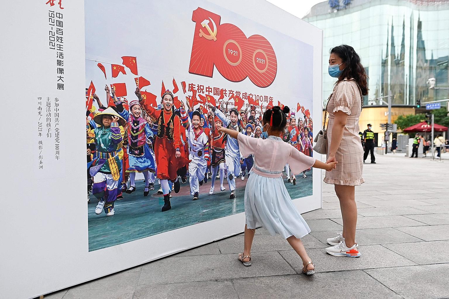A woman and a girl viewing an outdoor photography exhibition on the 100th anniversary of the founding of the Chinese Communist Party in Beijing earlier this month. A new book has watered down crises that would have otherwise called into question the 