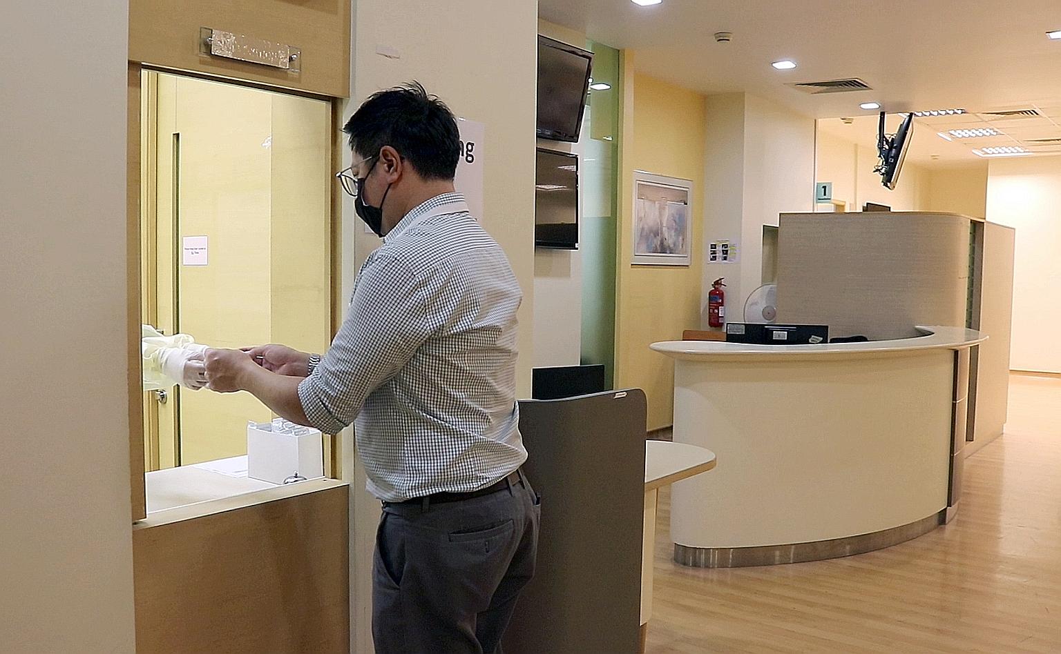 A hospital staff member demonstrating how a Covid-19 swab specimen is handed over to hospital staff for processing at the antigen rapid test centre at Singapore General Hospital.
