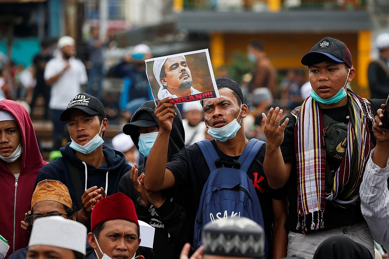 A supporter of Rizieq Shihab with a photo of the Indonesian hardline cleric who was jailed yesterday for spreading false Covid-19 information.