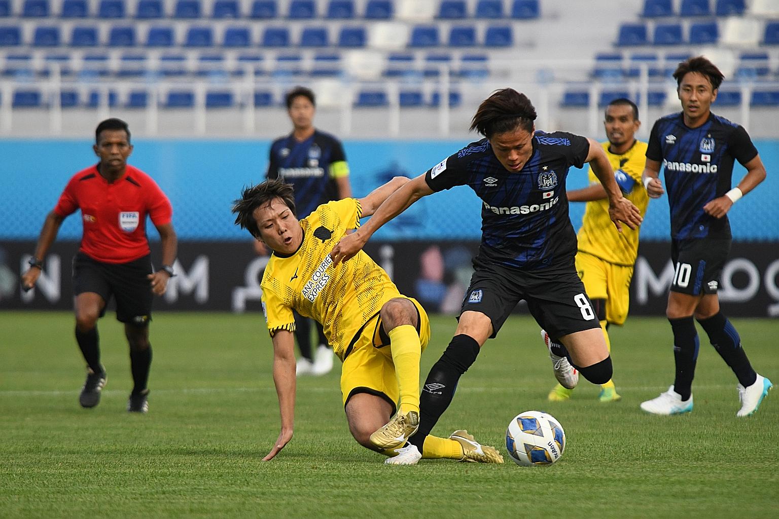 Tampines midfielder Kyoga Nakamura (in yellow) vying for the ball with Gamba Osaka's Kosuke Onose during their Asian Champions League Group H match last night. The Japanese side won 2-0.