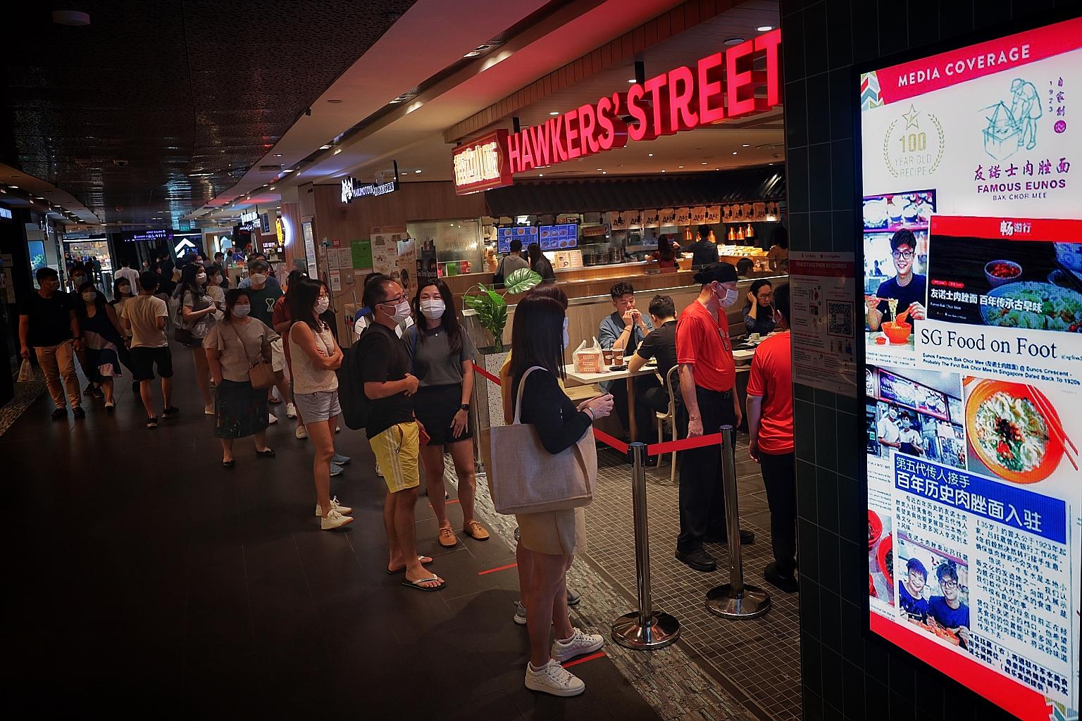 People waiting in line at Hawkers' Street in Ion Orchard mall yesterday on the first weekend since dining in was allowed to resume in groups of two. Many families took the opportunity to eat out as this is the last weekend of the school holidays. ST 