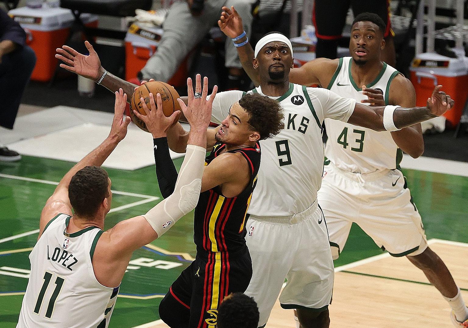 The Atlanta Hawks' Trae Young, after a 48-point performance in Game 1, is under pressure from the Milwaukee Bucks' Brook Lopez and Bobby Portis in Game 2. Young finished with a team-high 15 points.