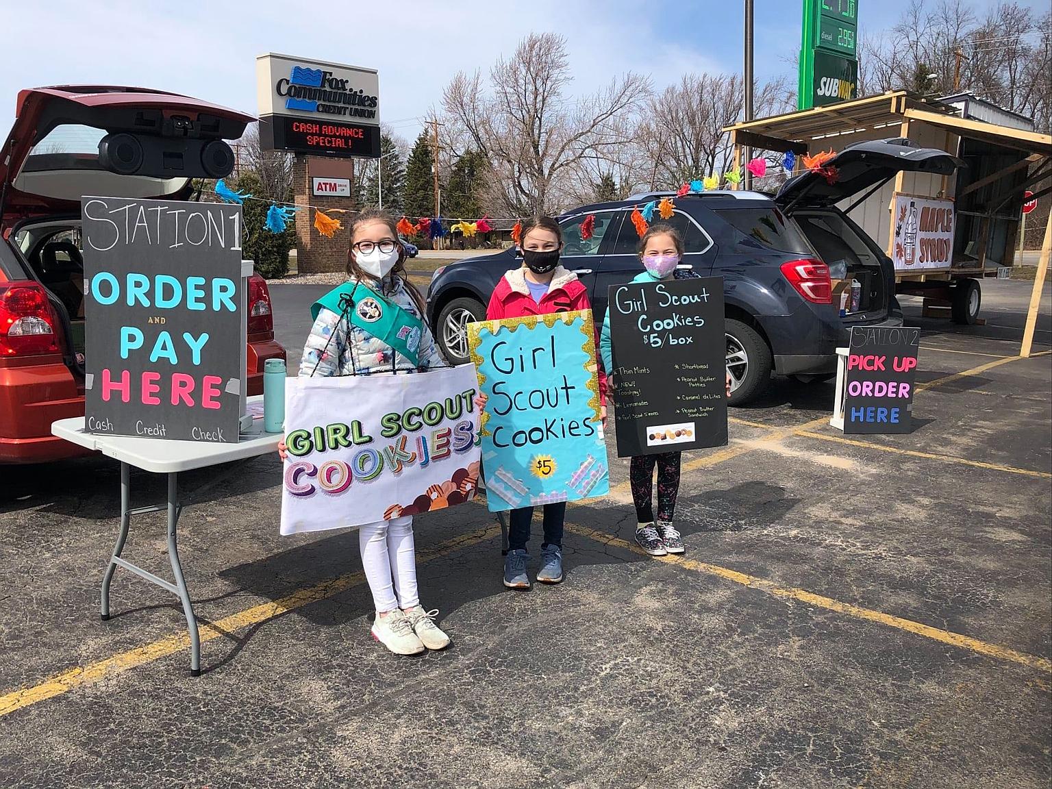 Girl Scouts from Wisconsin and Michigan selling cookies from makeshift booths.