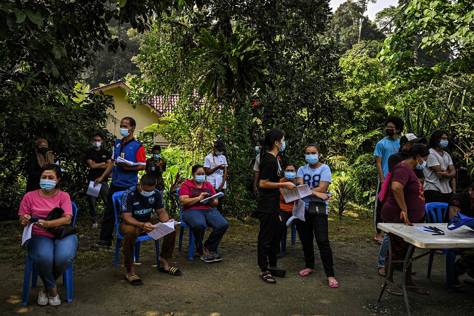 Indigenous people from the Temuan tribe waiting outside a Covid-19 vaccination centre in their village hall in Sungai Buloh, Selangor, yesterday. Malaysia's full lockdown, imposed on June 1 and originally set to end yesterday, will not be lifted unti