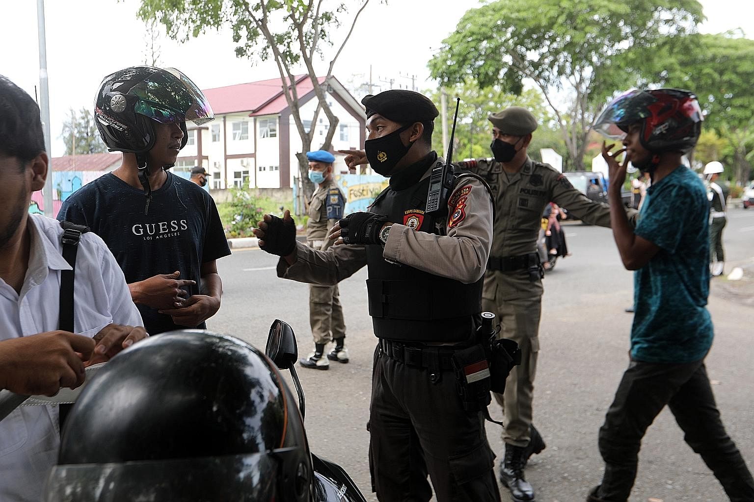 Aceh Joint Security Forces officers carrying out a security check and stopping motorists who failed to wear protective masks in public, in Banda Aceh, Indonesia, yesterday. A health worker administering the Sinovac Covid-19 vaccine at a shopping cent