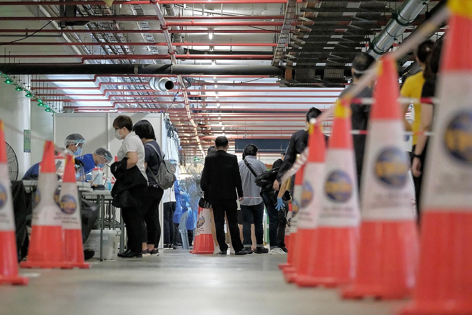 Staff and tenants from VivoCity and HarbourFront Centre waiting at a cordoned-off area in VivoCity's carpark yesterday to take their swab tests. Mandatory testing is under way for all who worked at the mall or the centre's retail mall between June 13