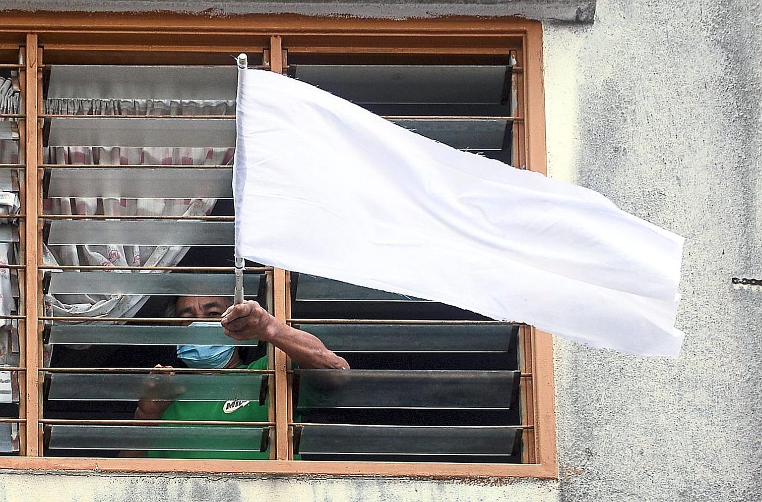 A man waving a white flag at his flat in Puchong, Malaysia. The movement called #benderaputih (white flag) on social media was started by Malaysians for those in need of food and other essentials. It signals the growing desperation of Malaysians, as 