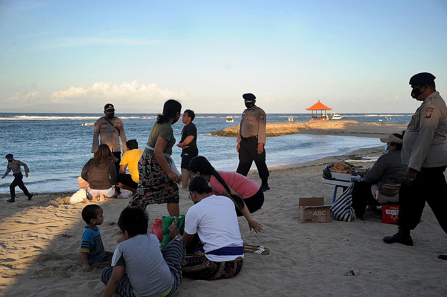 Police officers patrolling on a beach in Sanur yesterday to enforce new measures to curb the spread of Covid-19 on Indonesia's resort island of Bali. Public places like shopping malls, parks and places of worship were closed, while eateries could onl