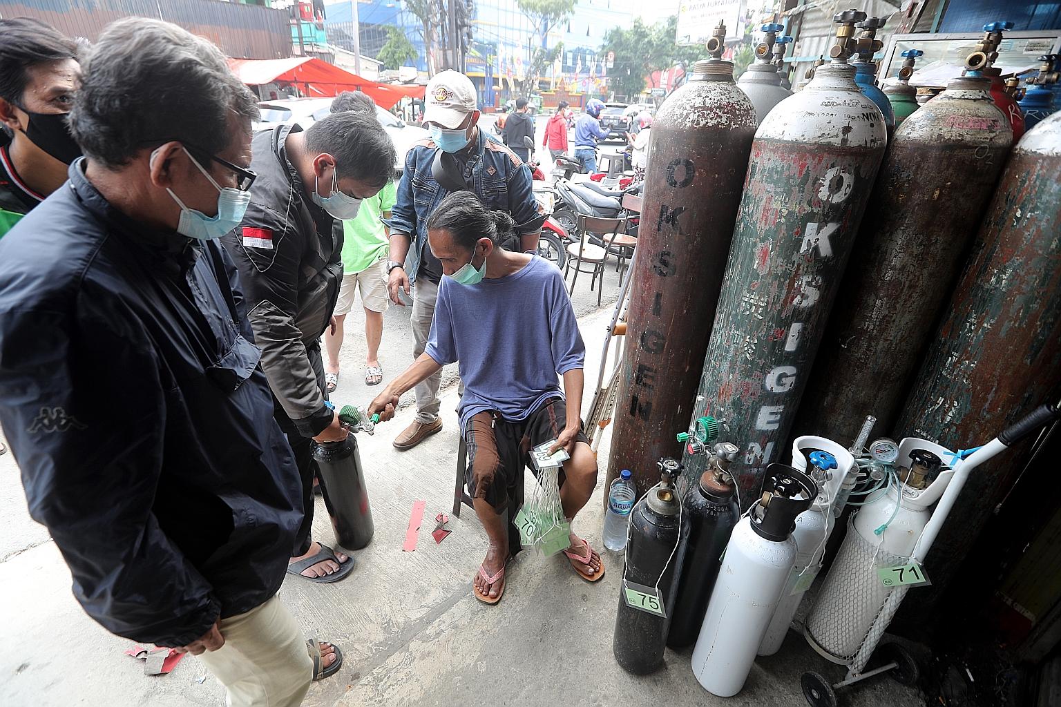 A worker in Jakarta checking the queue number on an oxygen tube at an oxygen refill shop. Indonesia's oxygen plants are operating at full capacity to produce 1,700 tonnes a day.