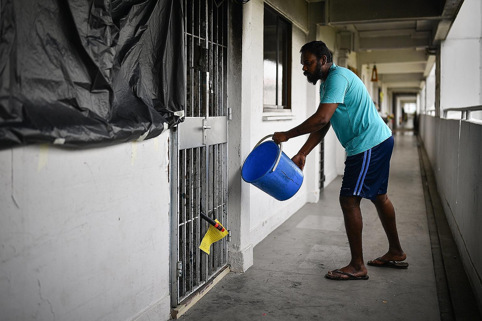 Mr Mageswaran R. Vadivaloo, 38, a cleaner who lives next door, demonstrating how he used a pail of water to try to put out the fire in his neighbour's flat.