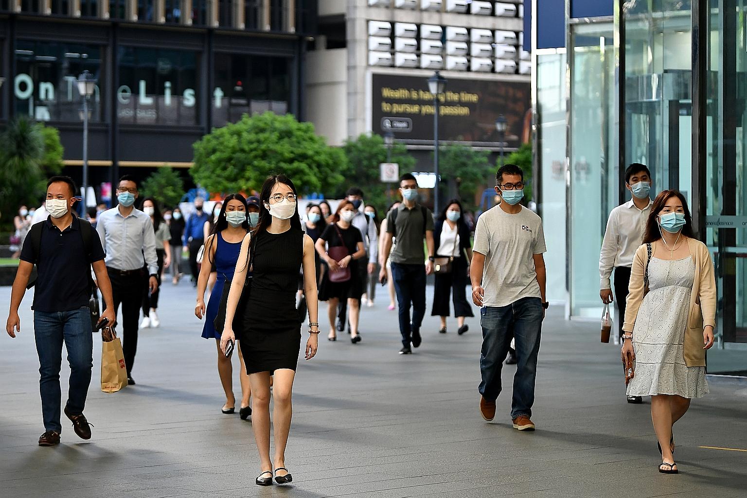 Office workers wearing face masks at Raffles Place in May. An uptick of Covid-19 cases that month led to tighter curbs, possibly putting a speed bump on the path to recovery for Singapore, said analysts.