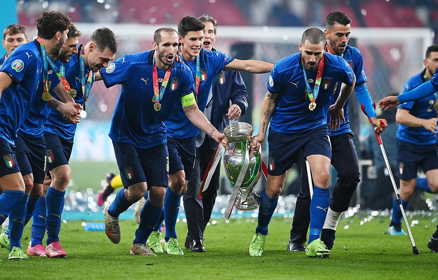 Giorgio Chiellini (left) and Leonardo Bonucci carrying the trophy as Italy teammates join in the celebration. The Azzurri edged out England 3-2 on penalties at Wembley to win their first European crown since 1968.