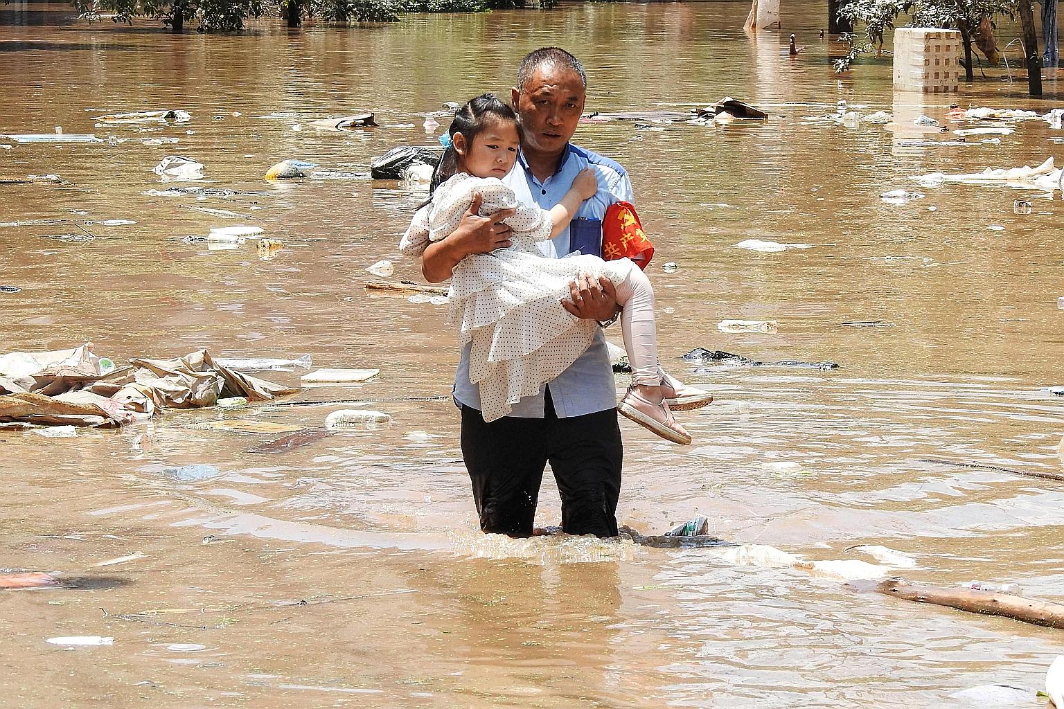 A village official evacuating a child from a flooded area on Monday following heavy rain in Dazhou, in China's south-western Sichuan province.