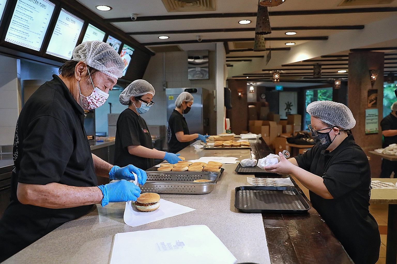 Service staff wrapping burgers yesterday at The Social Kitchen's Jurong Bird Park branch. Ms Jessica Szeto (at right), who has Down syndrome, was hired last November. She will receive further training there to progress in her career. ST PHOTO: KEVIN 