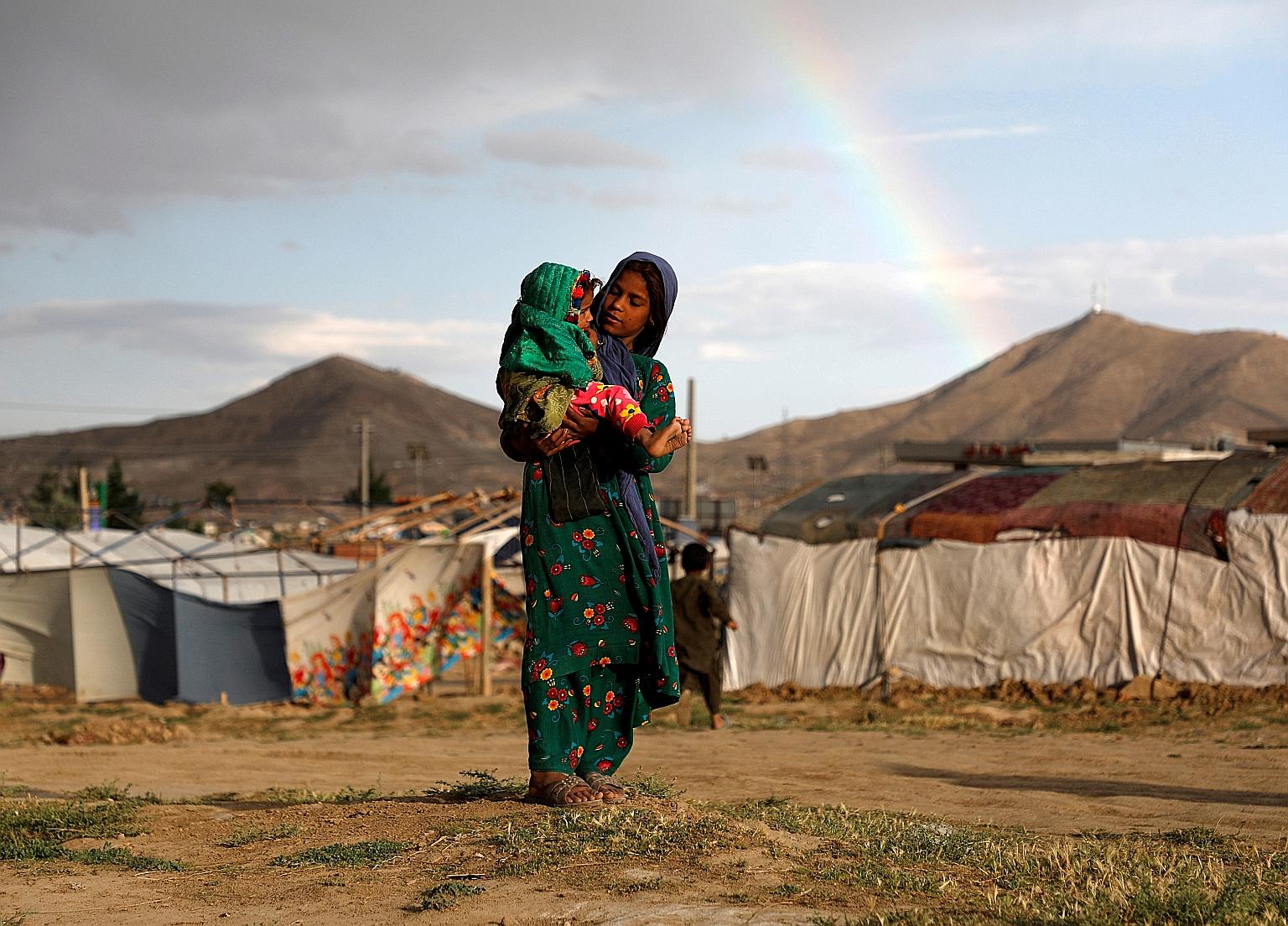 A 2019 photo of an internally displaced Afghan girl with a child at a camp on the outskirts of the capital Kabul. Several million Afghans have been displaced within their country over years of war.