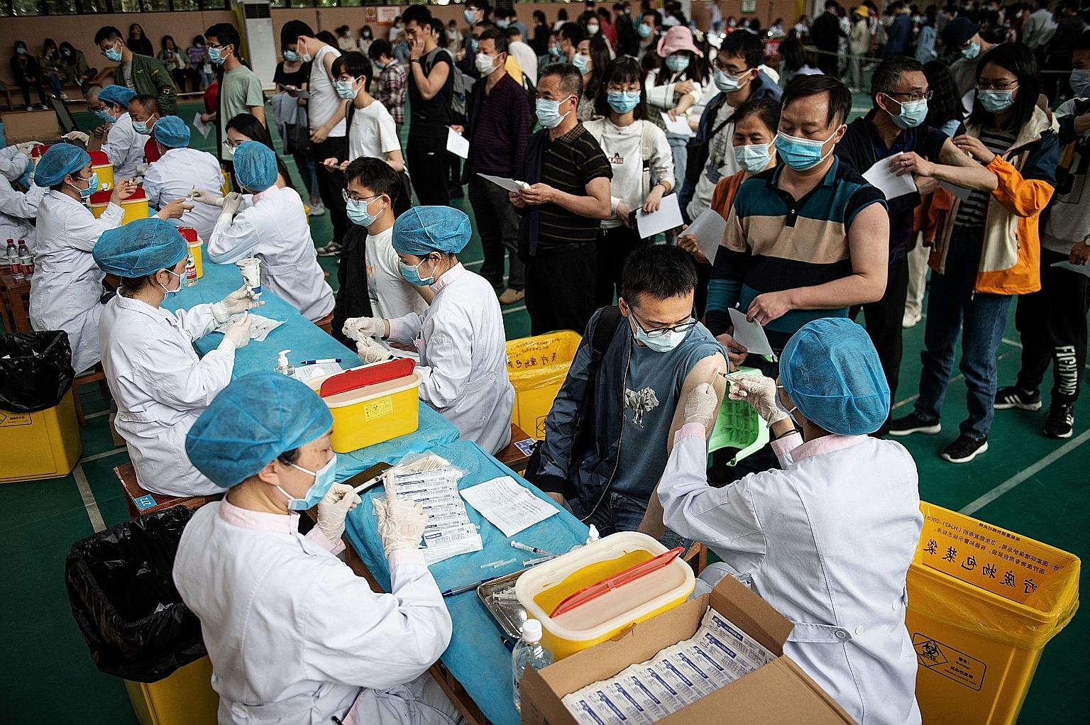 University students queueing for the Covid-19 vaccine in Wuhan in April. China's tough new rules to ban people who are not vaccinated from public spaces will be imposed on numerous second-tier cities. PHOTO: AGENCE FRANCE-PRESSE