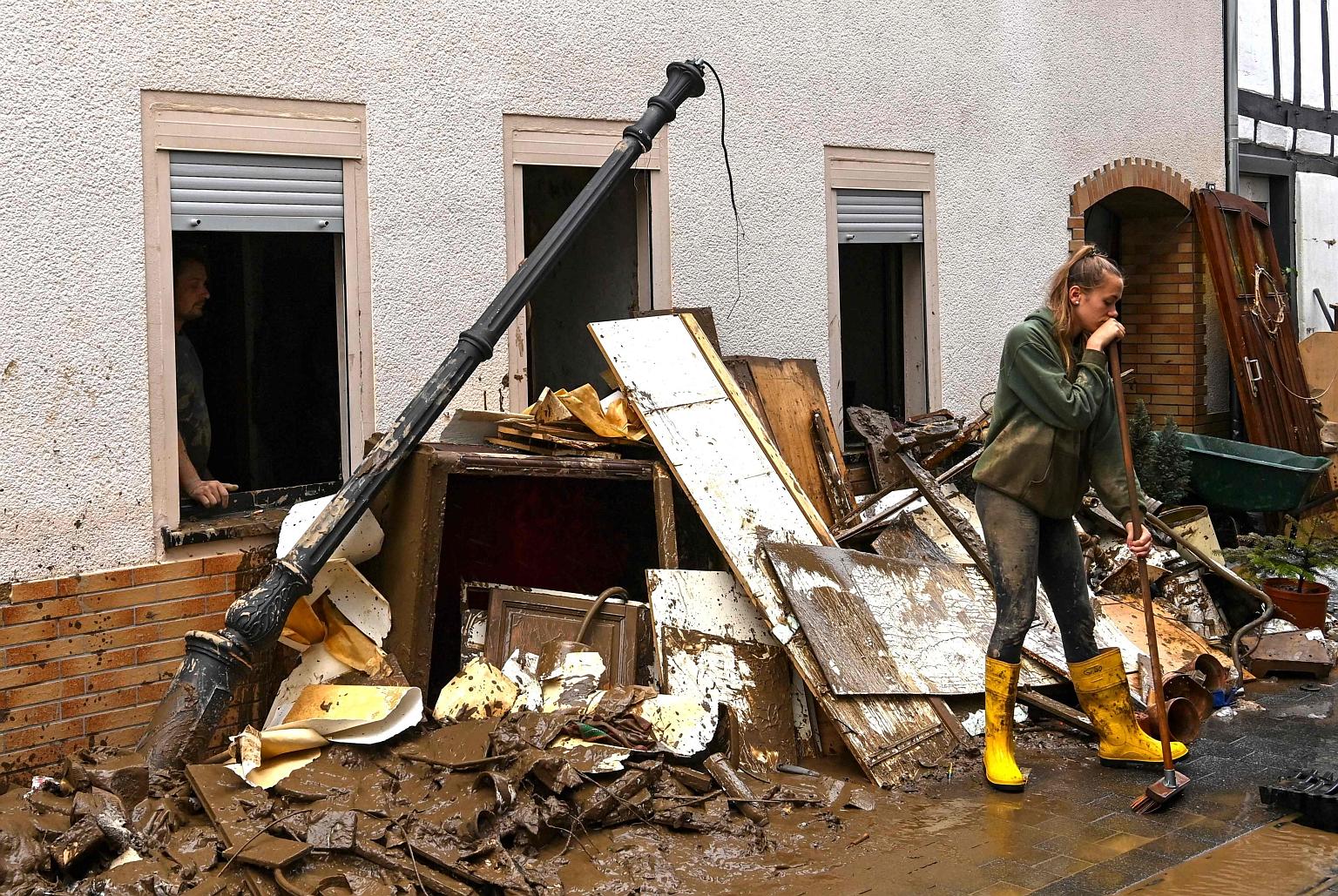 A young woman clearing up debris in a street in Germany's Bad Neuenahr-Ahrweiler on Friday. PHOTO: AGENCE FRANCE-PRESSE