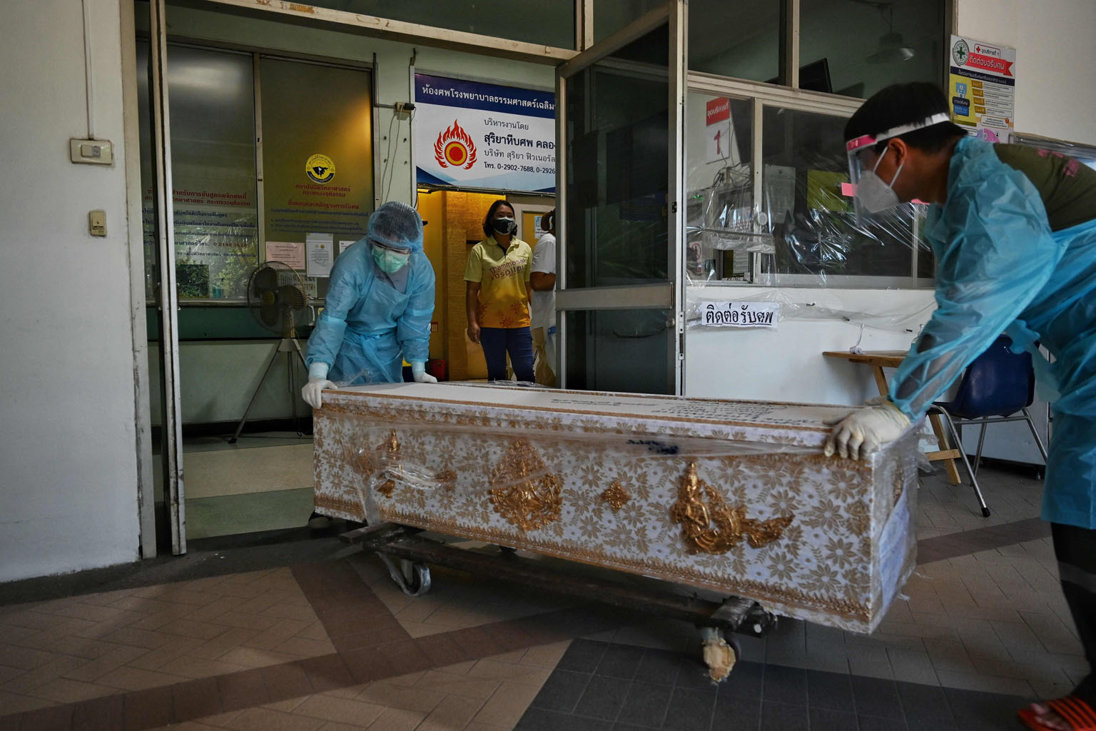 Workers moving a Covid-19 victim to the morgue of Thammasat Hospital in Pathum Thani province, north of Bangkok, yesterday. High-risk areas in Thailand are under the toughest curbs in more than a year.