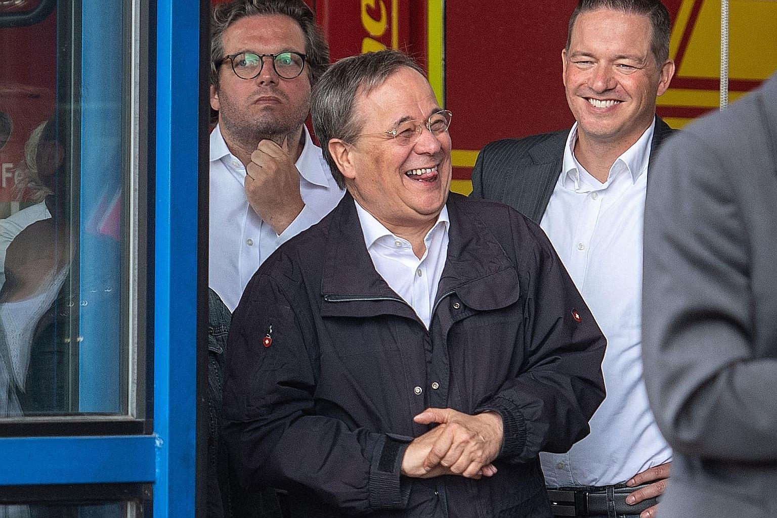 Mr Armin Laschet (centre) laughing while German President Frank-Walter Steinmeier (not pictured) delivered a speech in Erftstadt last Saturday. PHOTO: AGENCE FRANCE-PRESSE