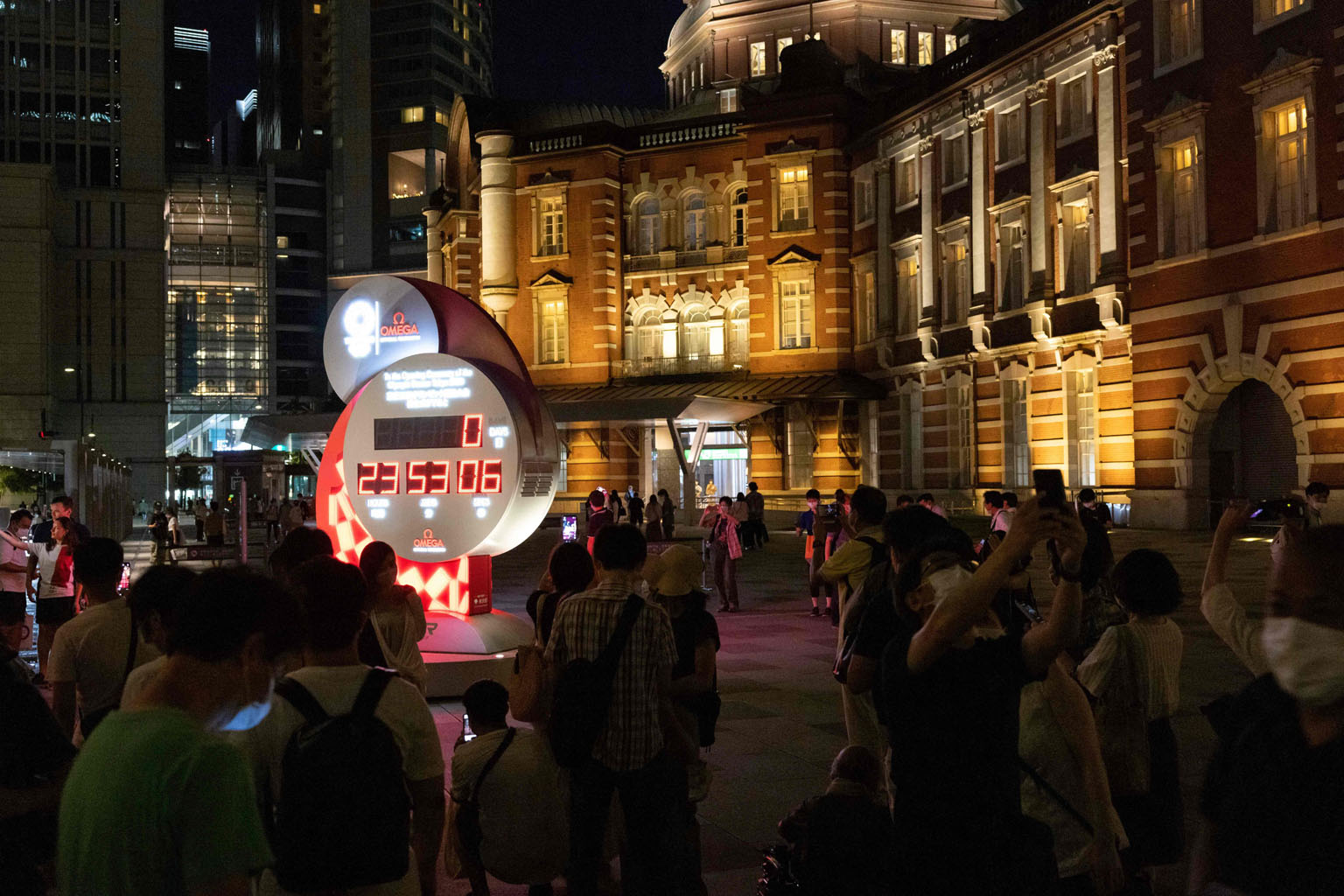People gather in front of the Olympic countdown clock yesterday, the eve of the opening ceremony for Tokyo 2020. The Games will finally raise their curtains today after a one-year delay due to the coronavirus pandemic.