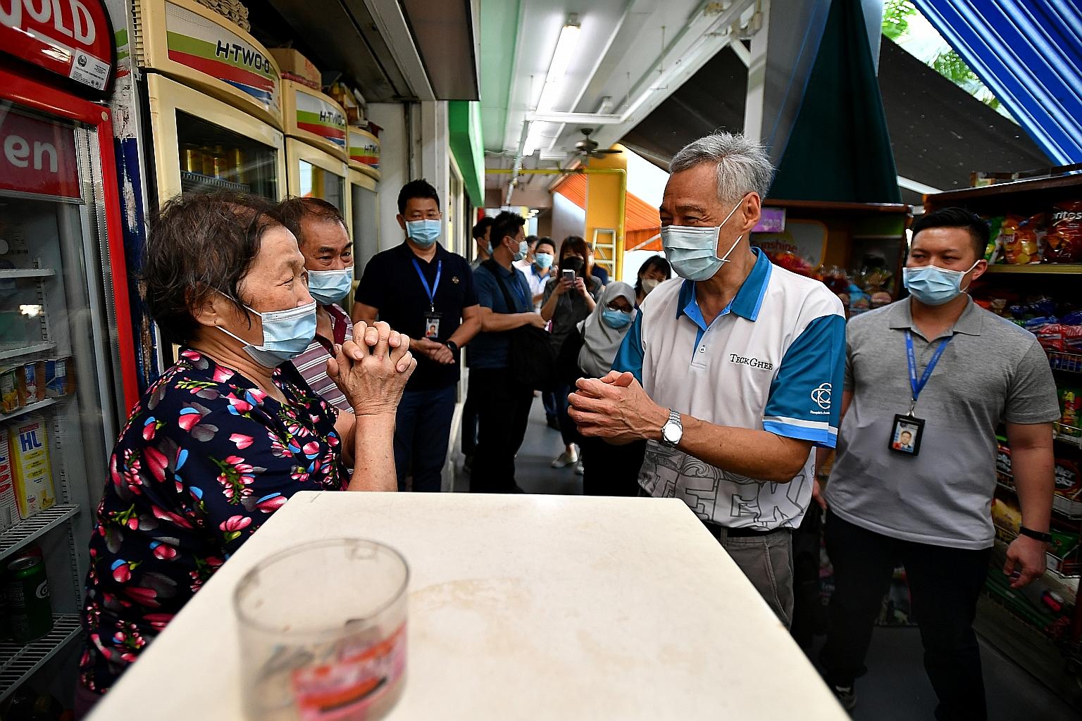Prime Minister Lee Hsien Loong greeting Madam Ng Kah Noi, 69, and Mr Koh Kiang How, 73, who both own Koh Huat Heng Minimart, at Block 456 Ang Mo Kio Avenue 10, yesterday. Mandatory Covid-19 testing is being conducted for residents of the block, where