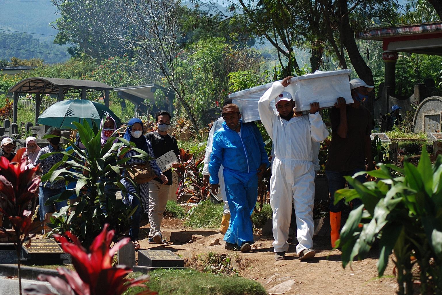 Gravediggers carrying the coffin of a man who died of Covid-19 as they headed towards a cemetery in Bandung, in Indonesia's West Java province, yesterday. Java and Bali account for more than 60 per cent of infections in the country, which has over 3.