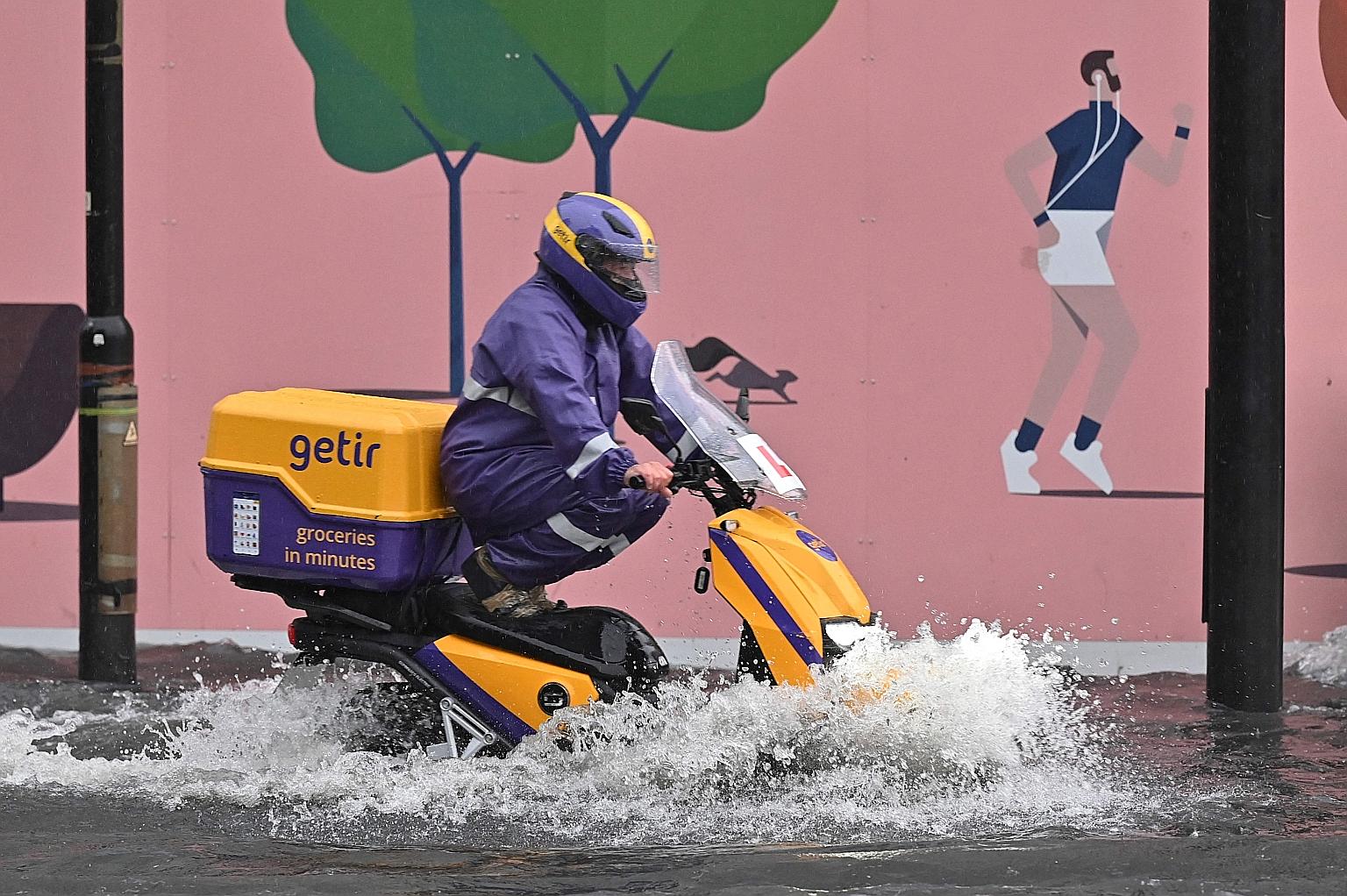 A motorcyclist riding through a flooded road in London's Nine Elms district on Sunday. Social media users posted videos of partially submerged vehicles. PHOTO: AGENCE FRANCE-PRESSE