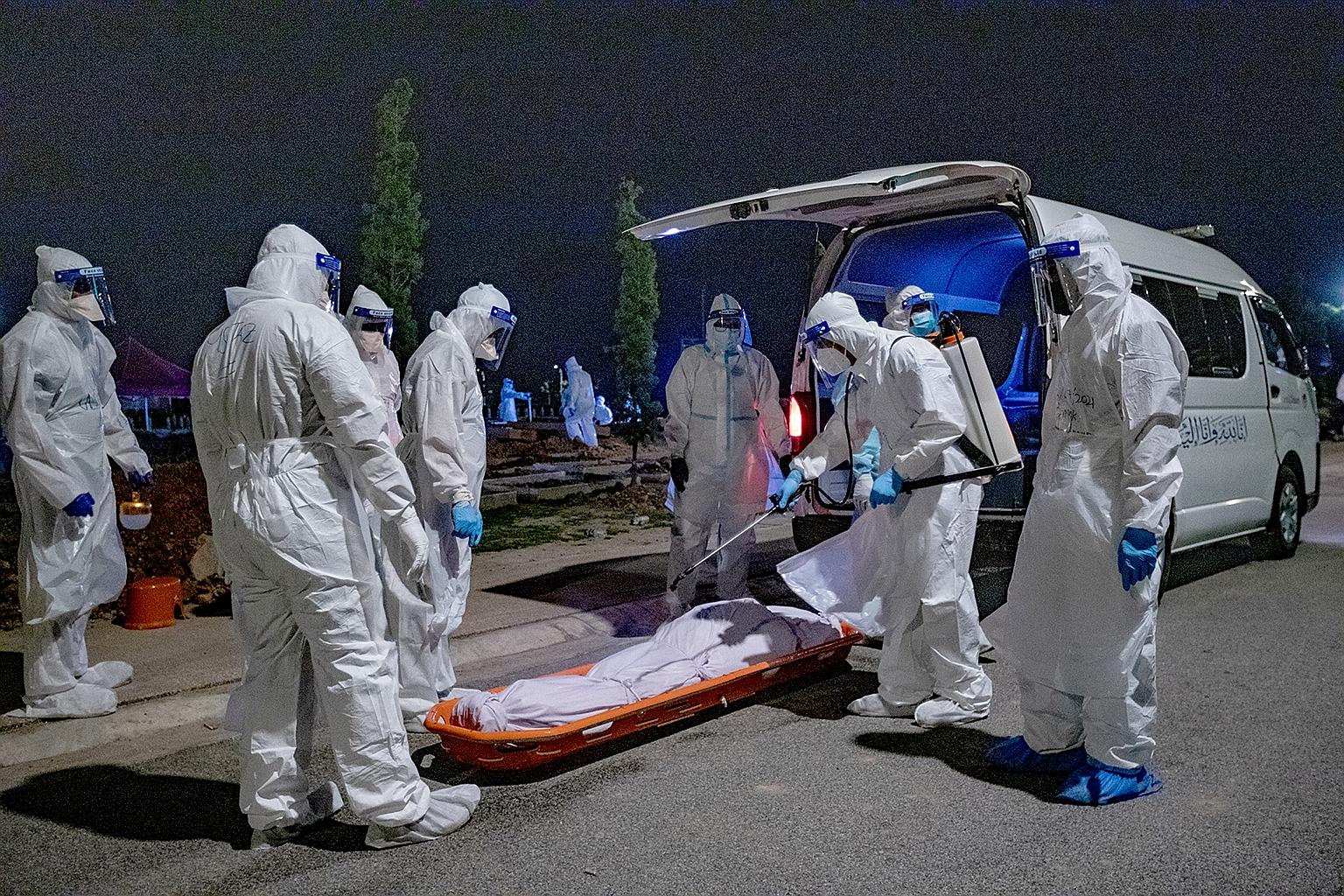 The body of a Covid-19 patient being sanitised before a funeral in Kuala Lumpur on July 16. Personal protective equipment is burned at the end of such funerals.