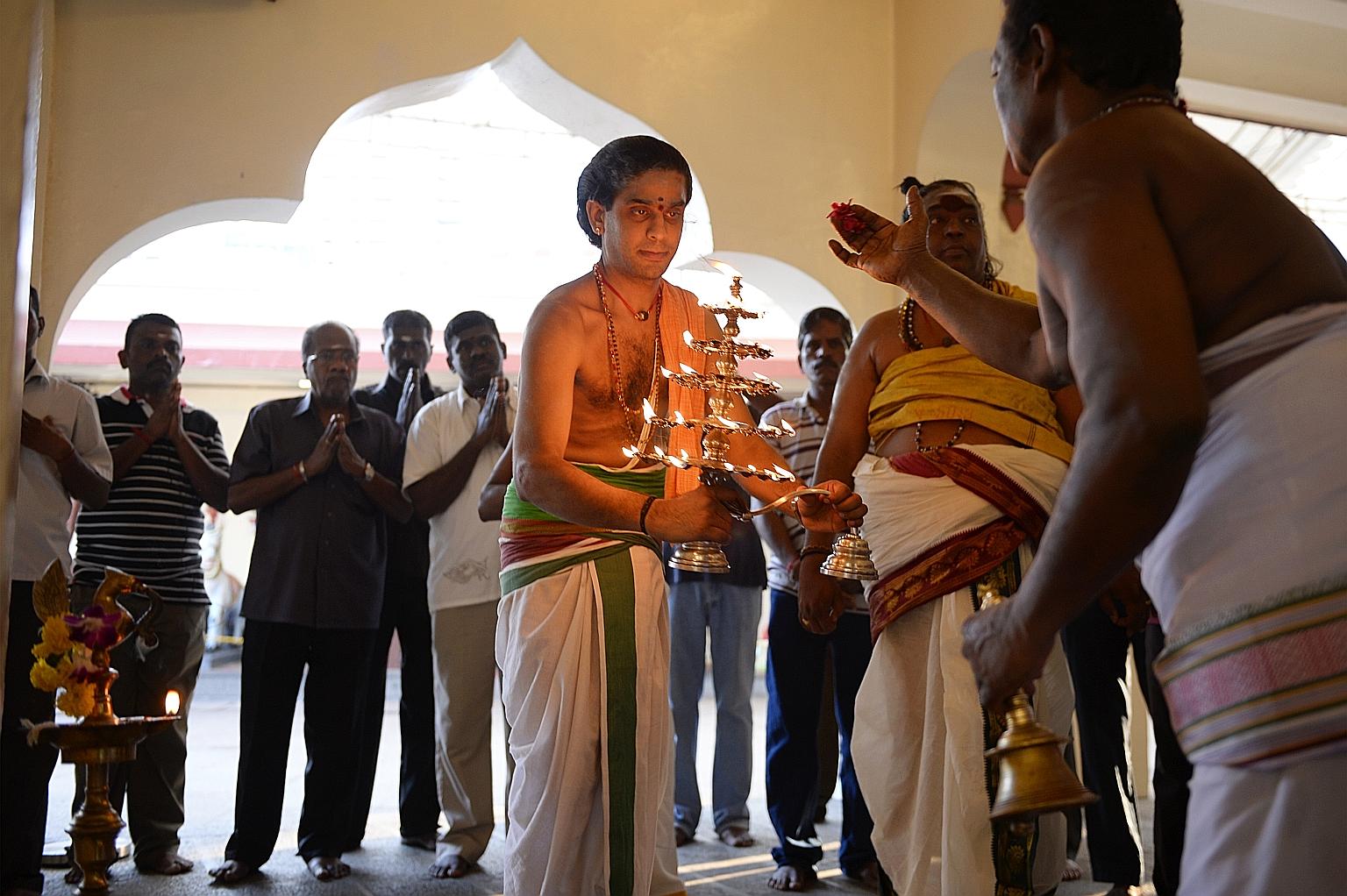 Hindu devotees praying as priests prepared an oil lamp for an offering to the gods at the Sri Mariamman Temple in South Bridge Road on April 14, 2014. Puthandu, the Tamil New Year, is traditionally celebrated on the first day of the Tamil month of Ch
