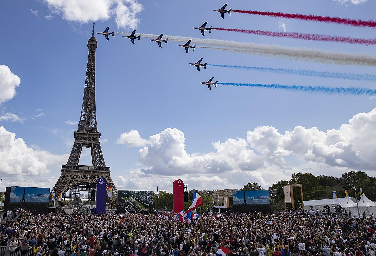 Alpha jets from the Patrouille de France aerobatics team flying over the Eiffel Tower as a crowd waving French flags gathers during the broadcast of the Olympic handover ceremony from Tokyo 2020 to Paris 2024 on Sunday. PHOTO: EPA-EFE