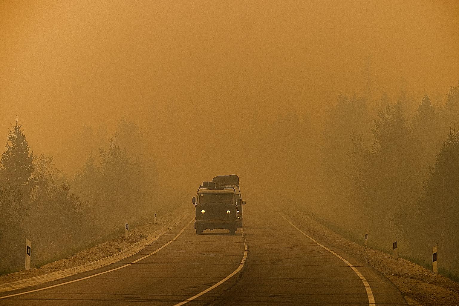 Vehicles driving on a road covered in smoke from nearby forest fires in Siberia's Sakha region last month. Russia's weather institute said this week that the region's situation "continues to deteriorate".