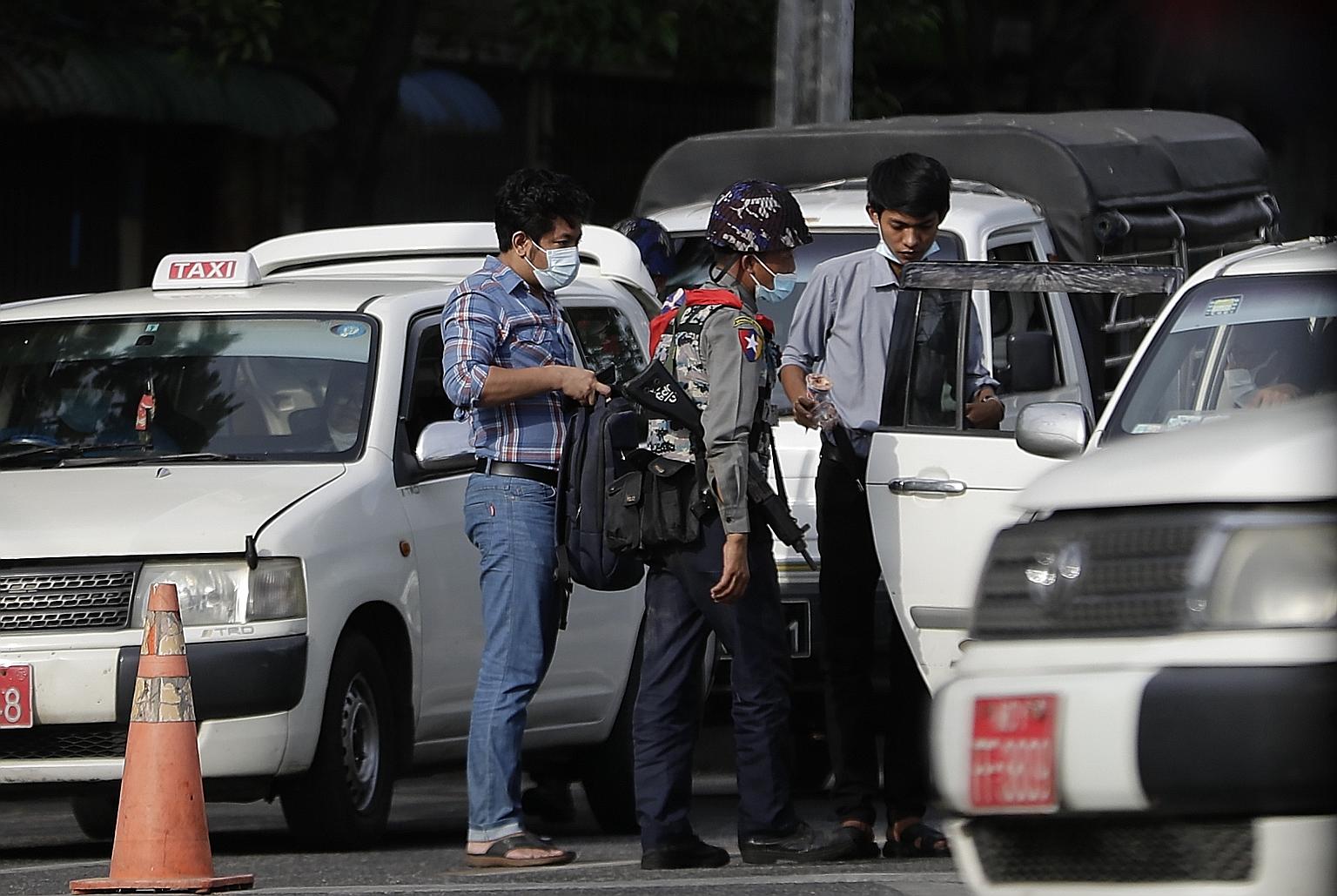 Police inspecting the belongings of cab passengers after several explosions occurred in a downtown area of Yangon on Tuesday. PHOTO: EPA-EFE