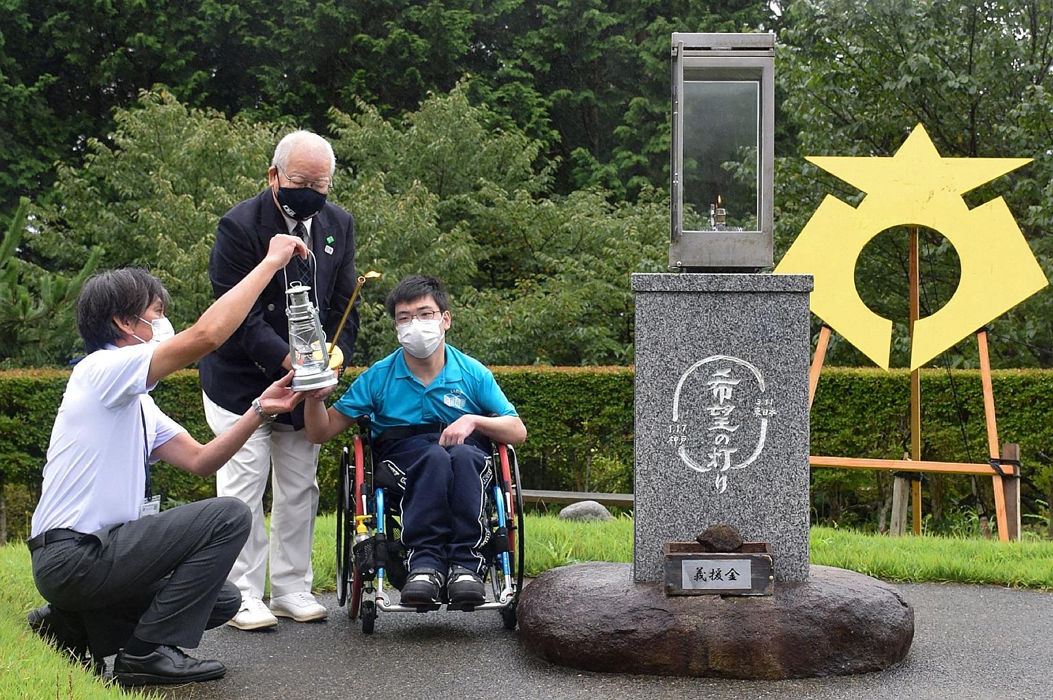 Officials with a torchbearer lighting a lantern at a Paralympic flame-lighting ceremony yesterday in Rikuzentakata, Iwate prefecture.