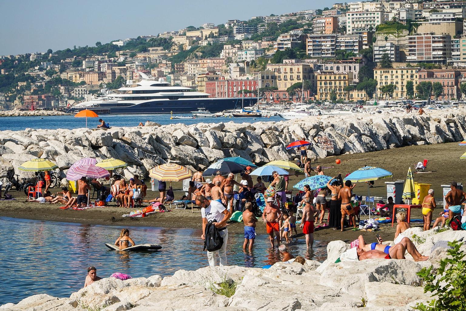 People spending time on the beach and the promenade yesterday in Naples, southern Italy. The searing heat is due to continue in Italy for several days and risks fuelling fires that have already plagued much of the country's south in recent weeks, not