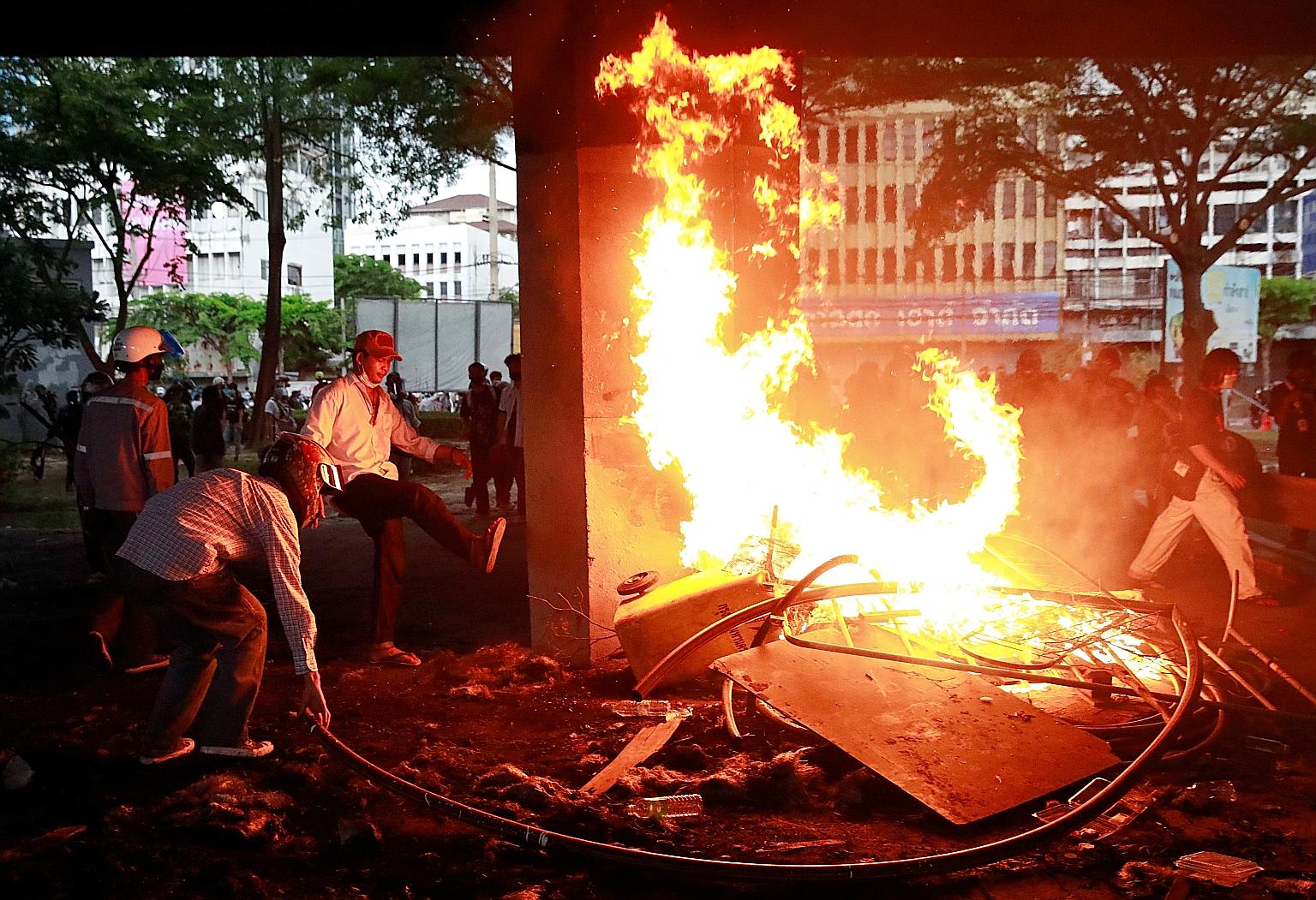 Demonstrators burning items during a protest in Bangkok yesterday over the Thai government's handling of the coronavirus outbreak. PHOTO: REUTERS