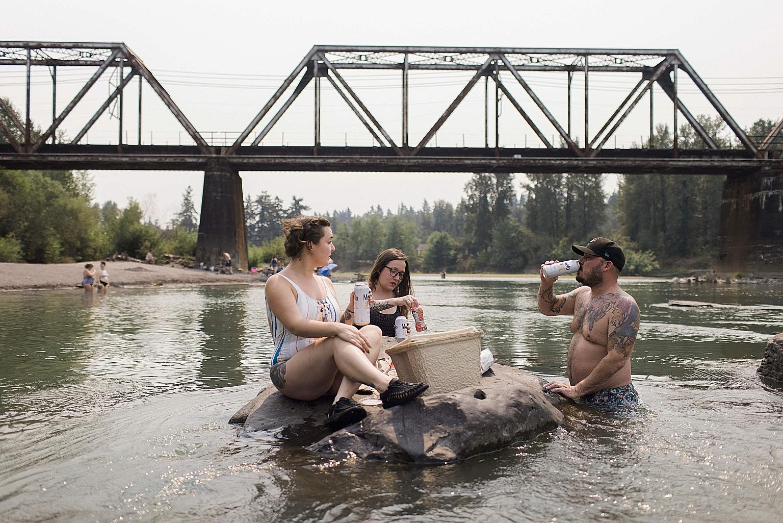 People cooling off in the Sandy River in Oregon, United States, on Friday. Last week, a United Nations climate science report from the Intergovernmental Panel on Climate Change provoked shock by saying the world is on course to reaching 1.5 deg C of 