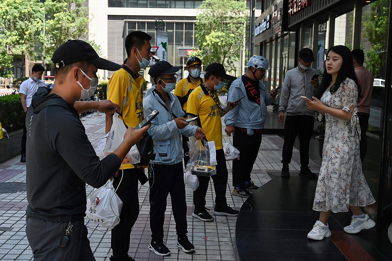 Delivery riders waiting to deliver food to workers at the entrance of an office building in Beijing in July.