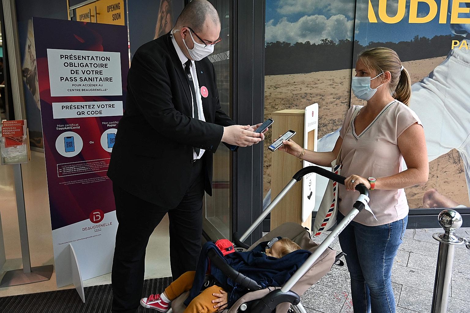 A Paris shopping mall employee checking the health pass of a customer on Monday. From this week, French police will be tougher when enforcing the use of the health pass in restaurants, trains and indoor public spaces, after being lenient when it was 