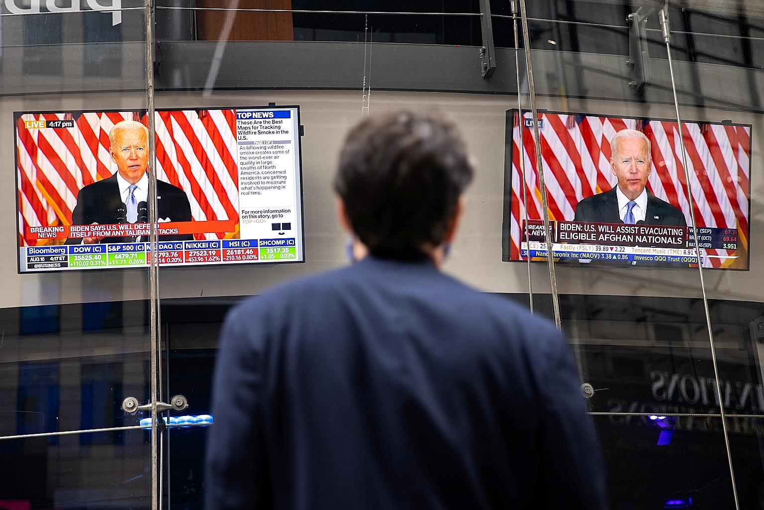 Giant TV screens in New York showing President Joe Biden talking about the crisis in Afghanistan on Monday. A Reuters/Ipsos poll shows Mr Biden's popularity fell as the Taleban entered Afghanistan's capital, Kabul, wiping away two decades of US milit