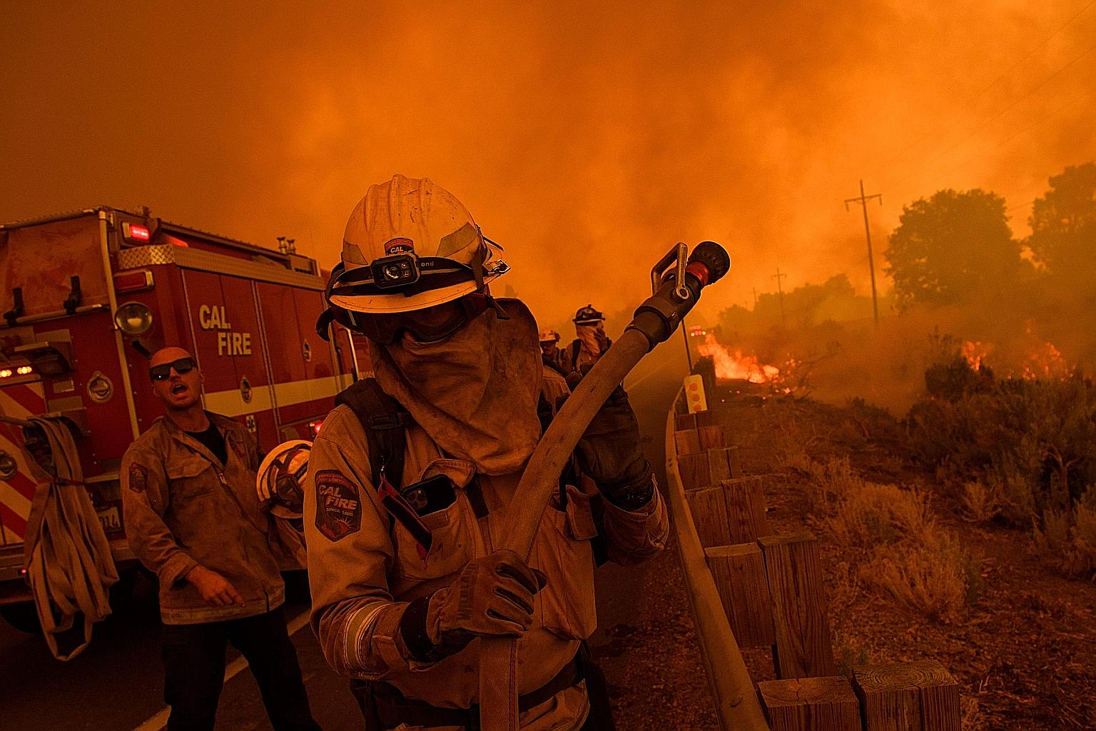 Cal Fire firefighters setting a hose line as they try to contain a fire near Milford, California. On Monday, California crossed a milestone of one million acres razed, the earliest it has reached that mark in history. Crews are battling 11 large blaz