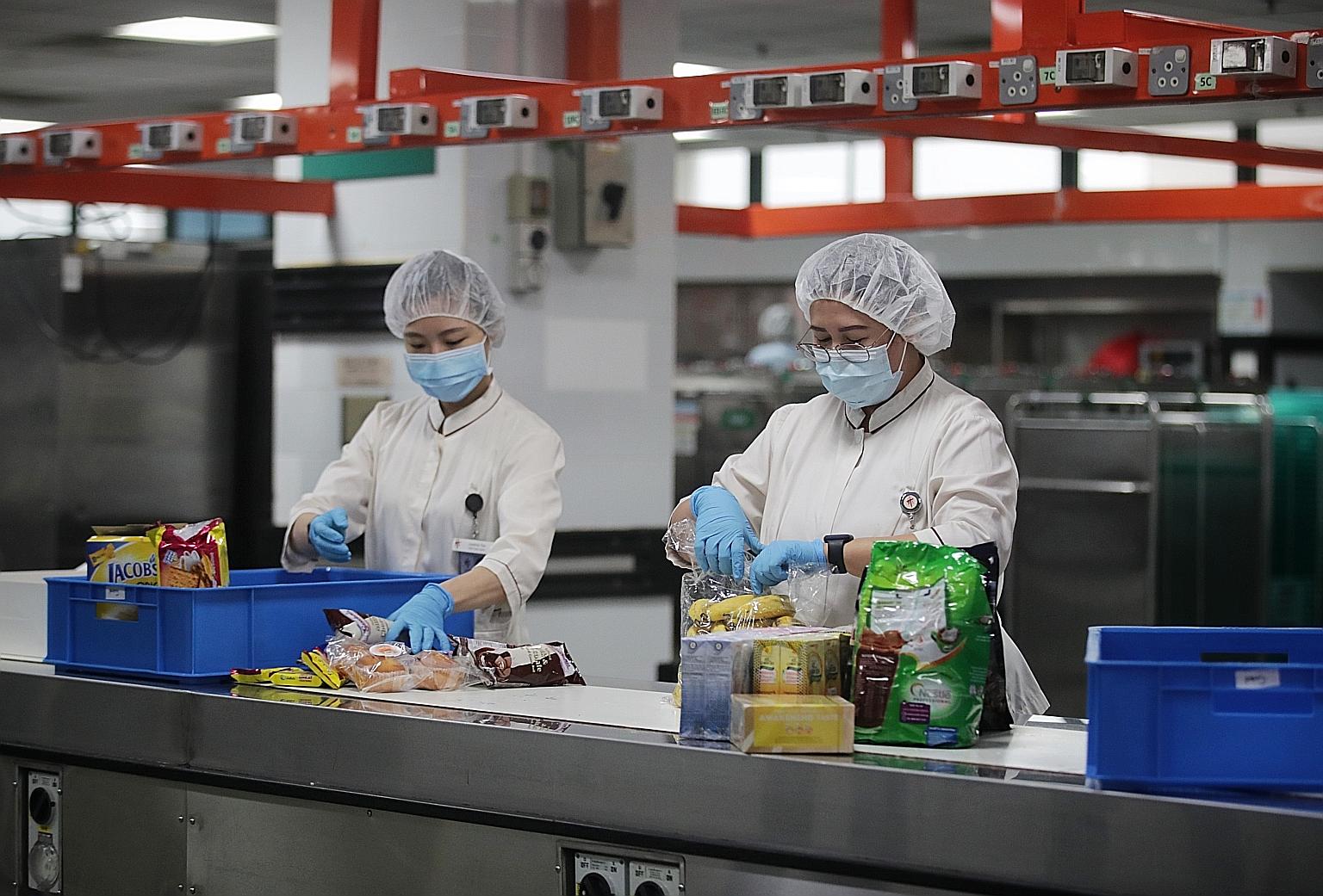 Assistant supervisor Maala Maria Antonnette (right) packing snacks such as fruits and packet drinks into carts at Tan Tock Seng Hospital.