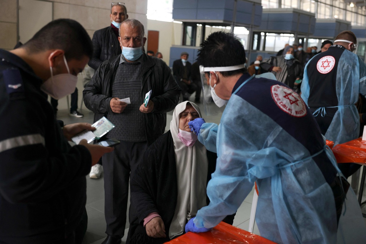 <p>A Palestinian woman is tested for COVID-19 by an Israeli medic before entering in to Israel by the Erez border crossing from the Hamas-controlled Gaza strip on December 20, 2021, as Israel allows merchants and humanitarian cases to enter the country. (