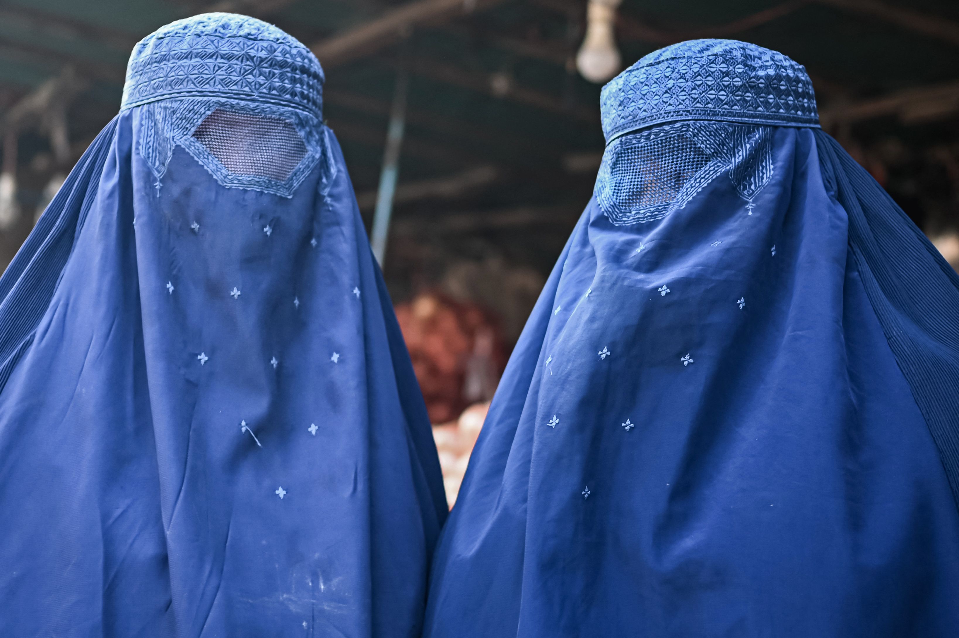 <p>Afghan burqa-clad women are pictured at a market in Kabul on December 20, 2021. (Photo by Mohd RASFAN / AFP)</p>