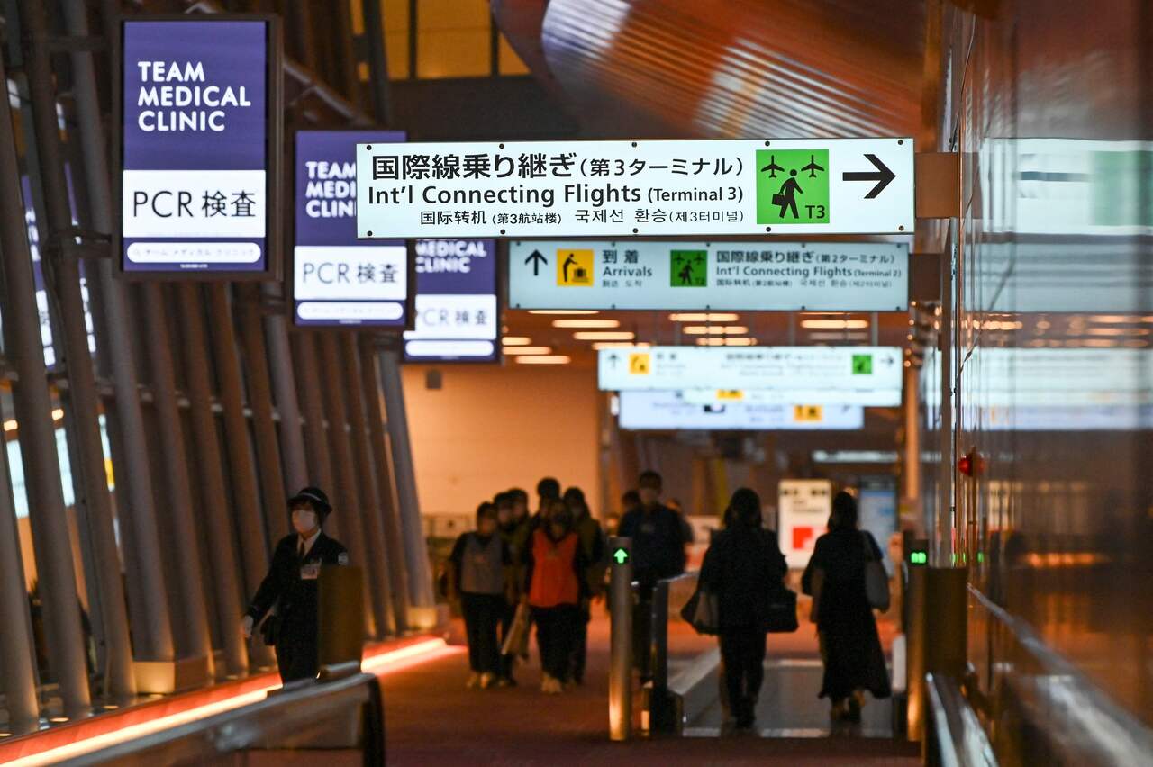 <p>Quarantine support members walk on an international flight arrival floor at Tokyo's Haneda airport on December 1, 2021, as Japan suspended all new flight bookings into the country in response to the Omicron Covid variant. (Photo by Kazuhiro NOGI / AFP)