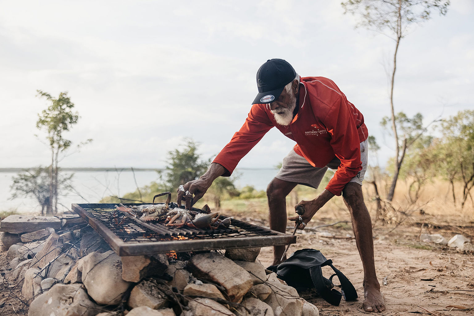 Bardi Jawi Indigenous man cooking a bush tucker feast outdoors on a grill 