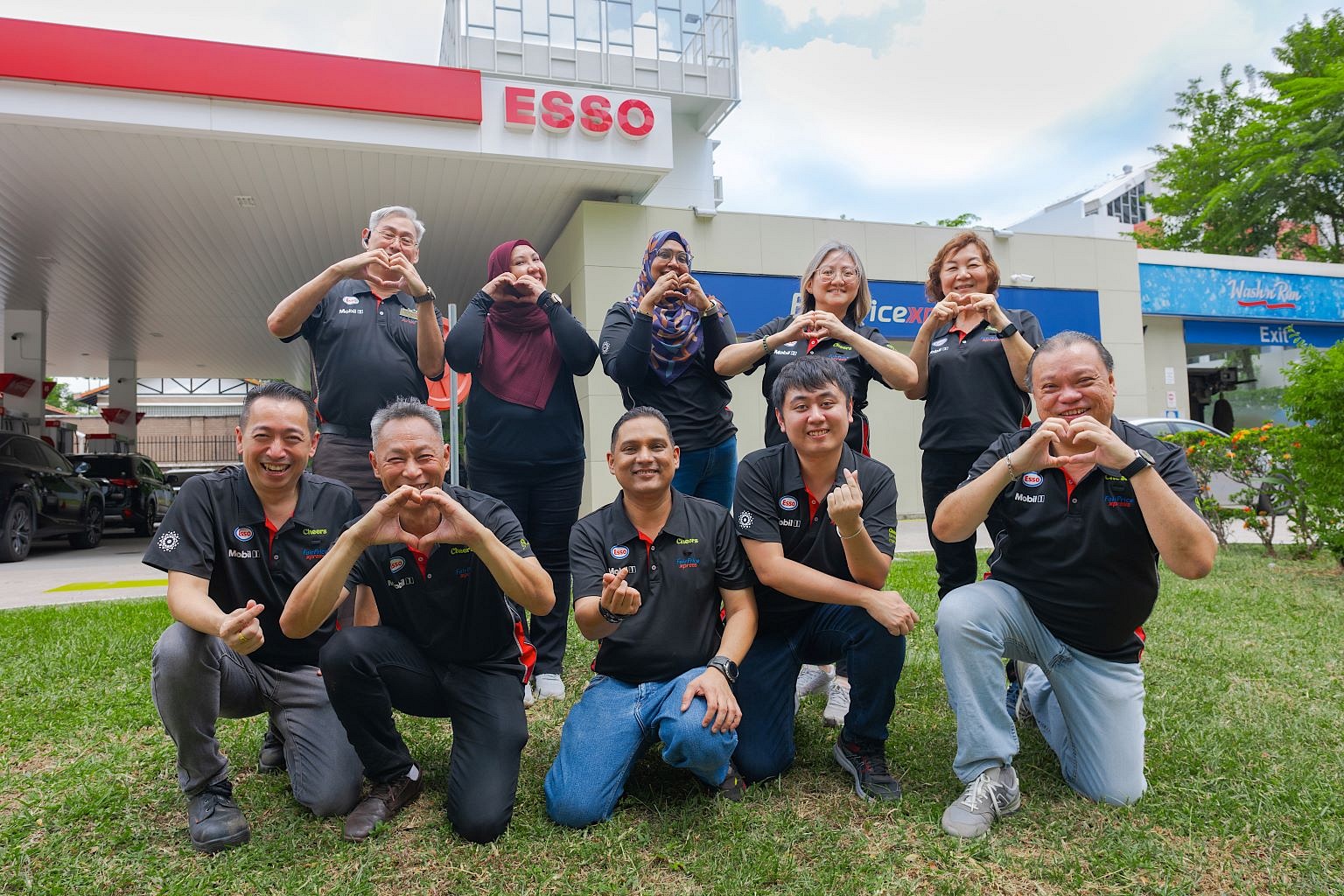 Esso employees standing in front of an Esso station cheering