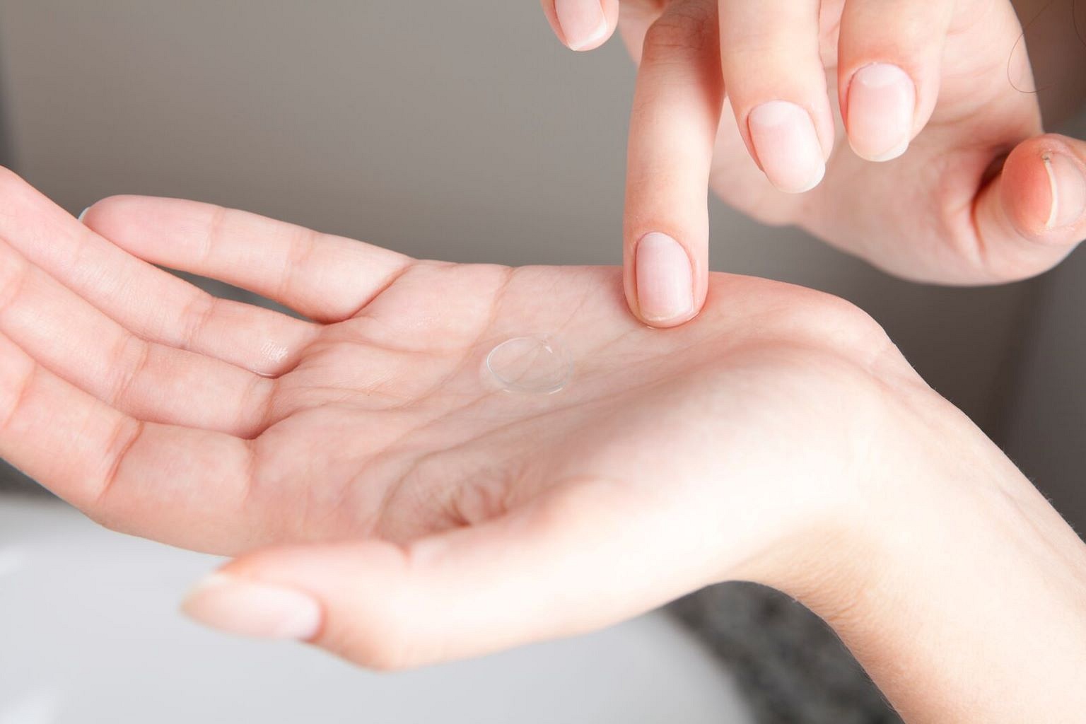 Woman with Acuvue Oasys Max-1 Day contact lense on the palm of her hands