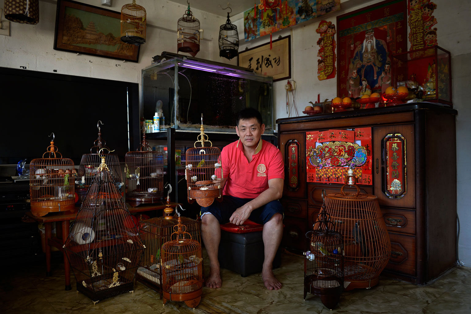 Mr Eric Ang, 46, with his pet birds in his living room. Mr Ang has lived in the estate all his life, and says that if he had the choice, he would not leave. He currently spends his time at home taking care of his bedridden elderly mother.