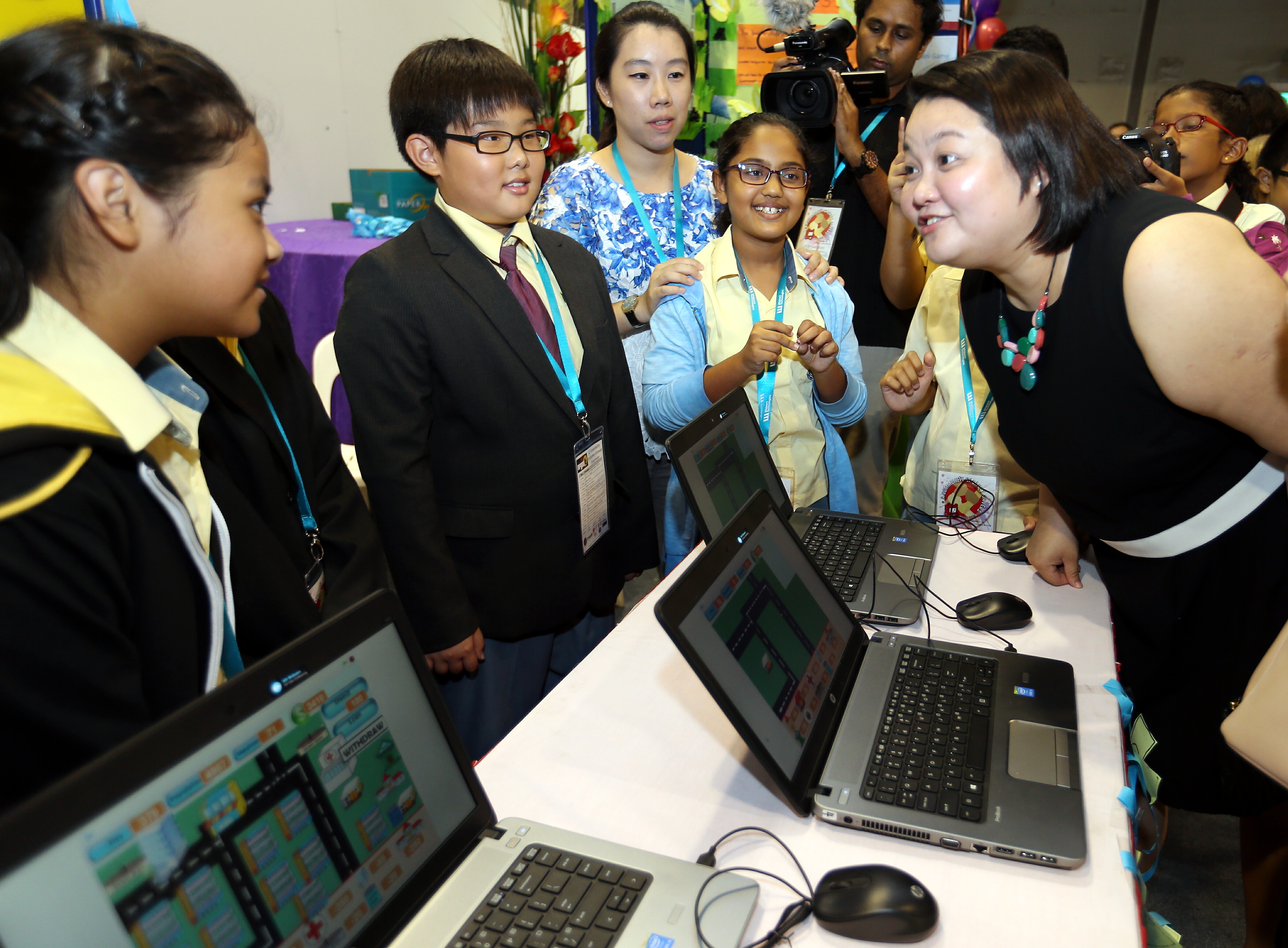 Ms Tan Swee Leng (right) of the People's Association, chatting with pupils yesterday at the Singapore Science Centre, where the children from Primary 4 to 6 showed the digital games they produced using a simple coding tool called Scratch to create ga